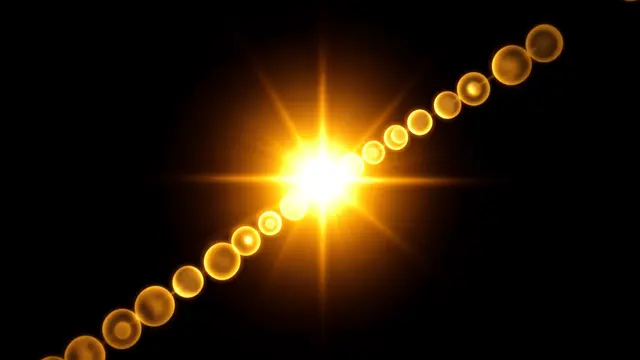 Warm golden sun flare with a diagonal chain of soft round lens orbs set against a pure black background