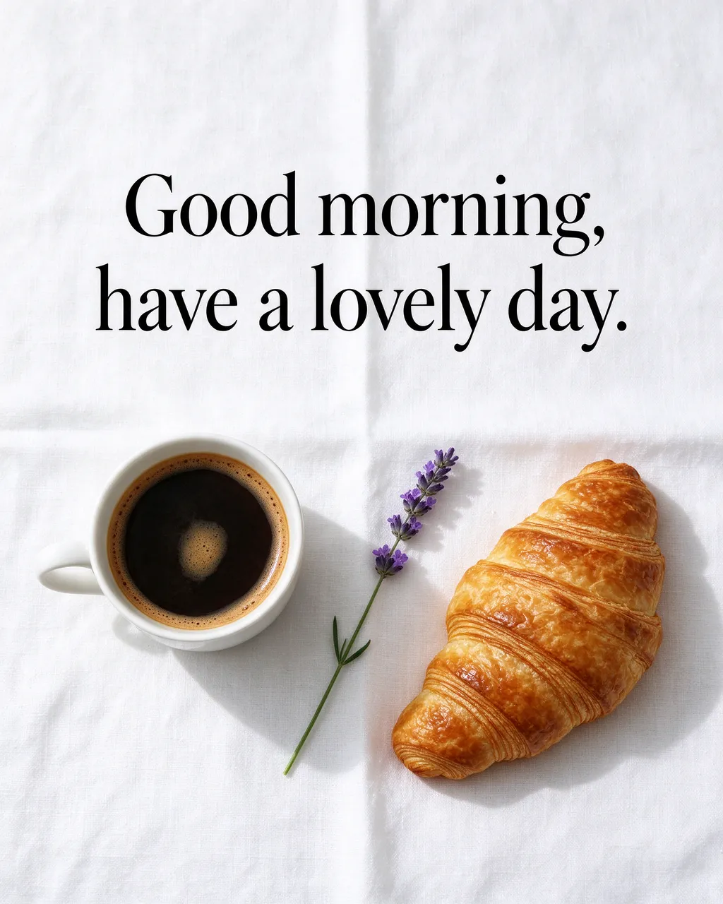 Flat lay of coffee, croissant and lavender on a white linen cloth with the text "Good morning, have a lovely day."