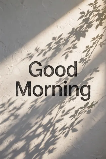 "Good Morning" text over sunlit textured white wall with soft plant leaf shadows
