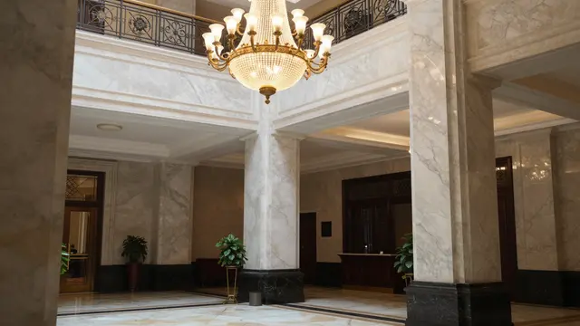 Ornate crystal chandelier hangs above polished marble columns in a luxurious hotel lobby