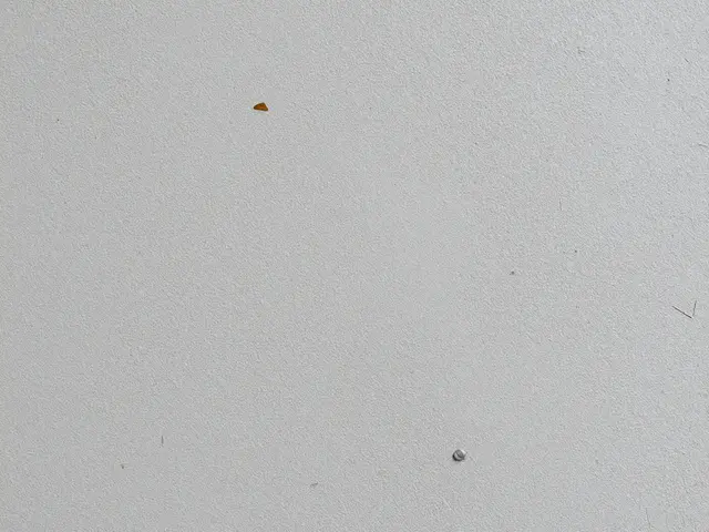 Full frame close-up of a matte light gray pressed chipboard surface with scattered tiny flecks