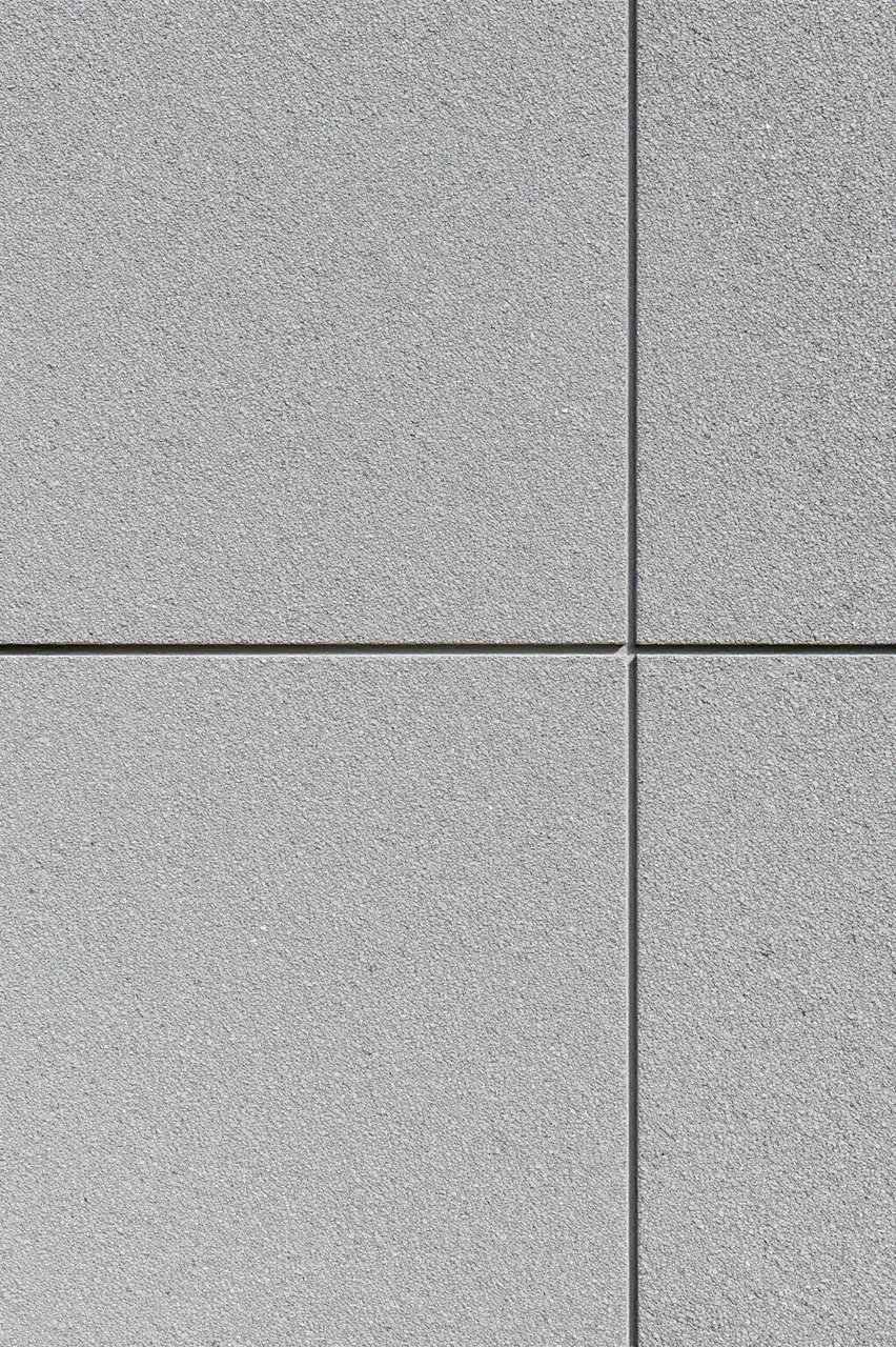 Close-up full frame view of gray pebbledash render wall arranged in panel sections with flat even lighting