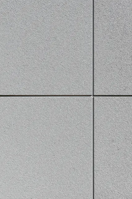 Close-up full frame view of gray pebbledash render wall arranged in panel sections with flat even lighting