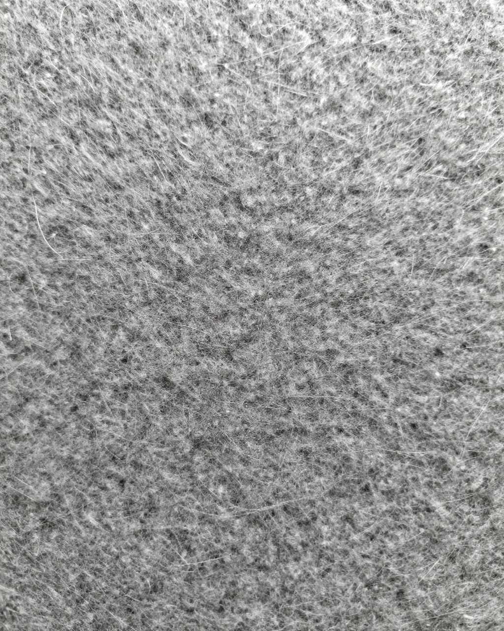 Full frame close-up of soft gray wool felt with visible fine fuzz fibers catching light