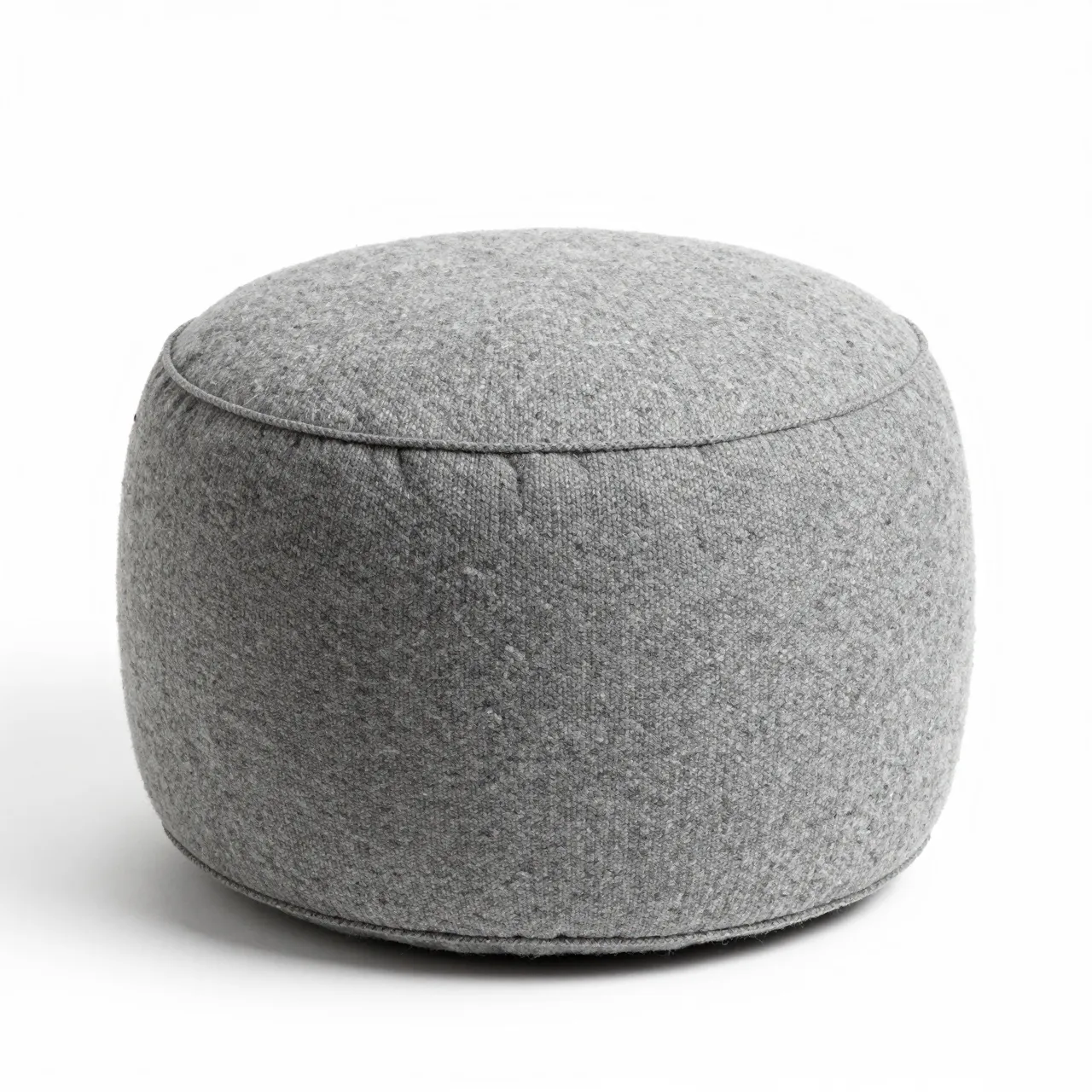 A round soft gray fabric pouf sits isolated against a plain white studio background