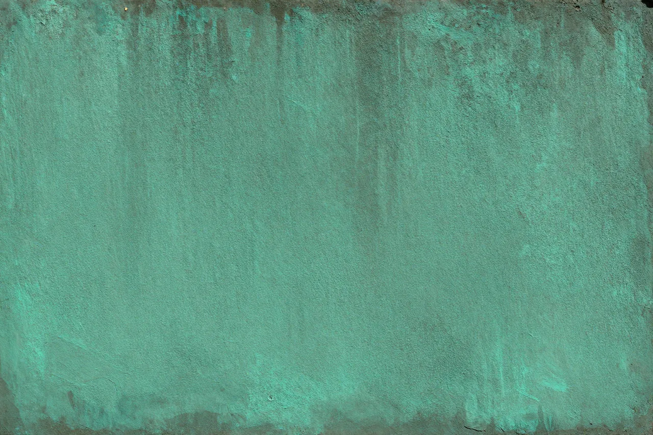 A full frame close-up of weathered copper covered in vibrant verdigris patina streaks