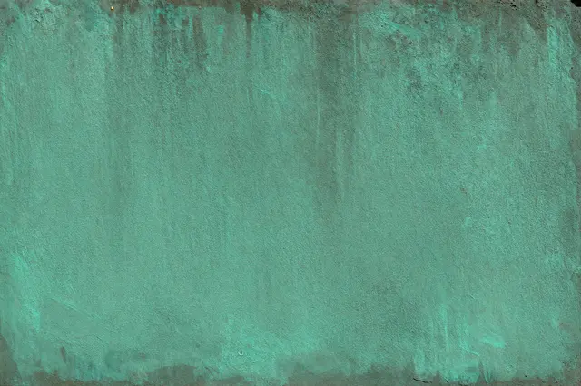 A full frame close-up of weathered copper covered in vibrant verdigris patina streaks