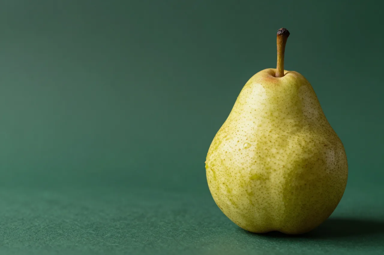 A single ripe yellow-green pear rests on the right of a muted dark green background with empty copy space to the left.