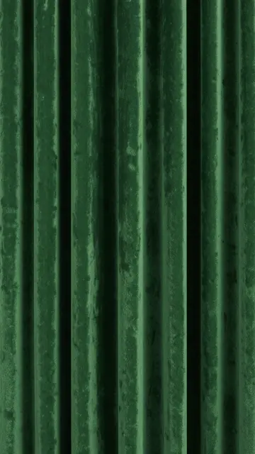 Close-up of pleated dark green velvet fabric with soft sheen and vertical folds