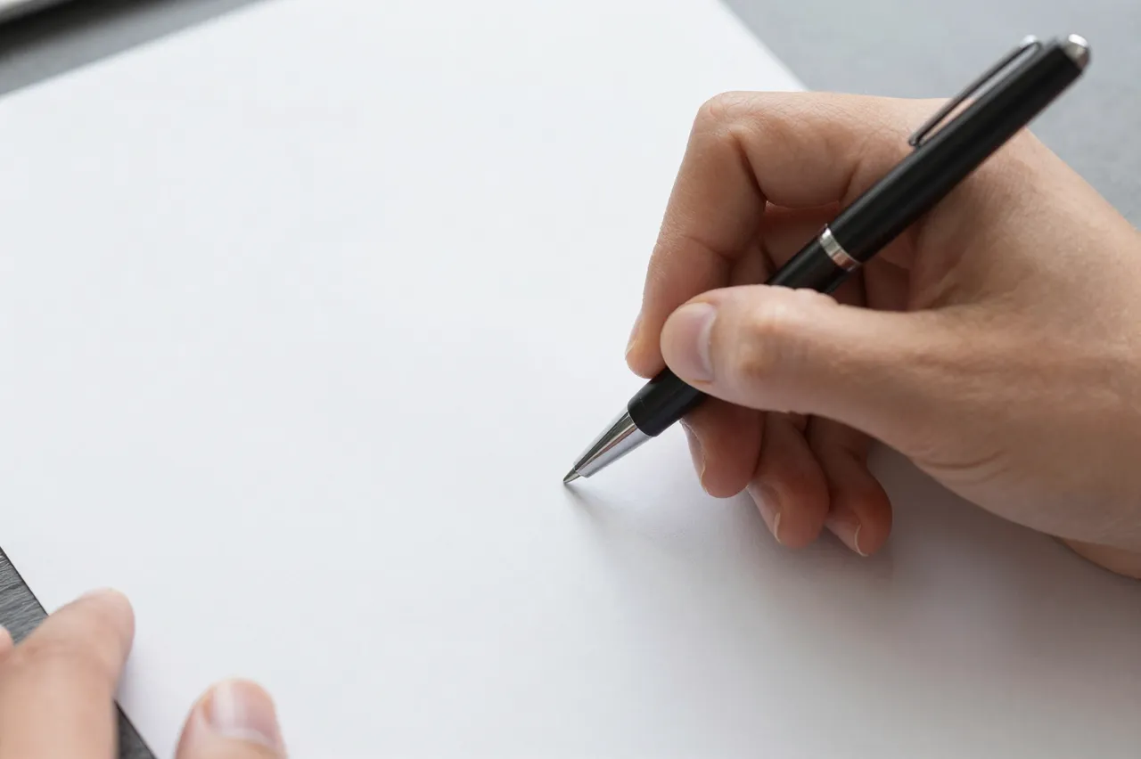 Close-up of two hands holding a pen over blank white paperwork, ready to write.