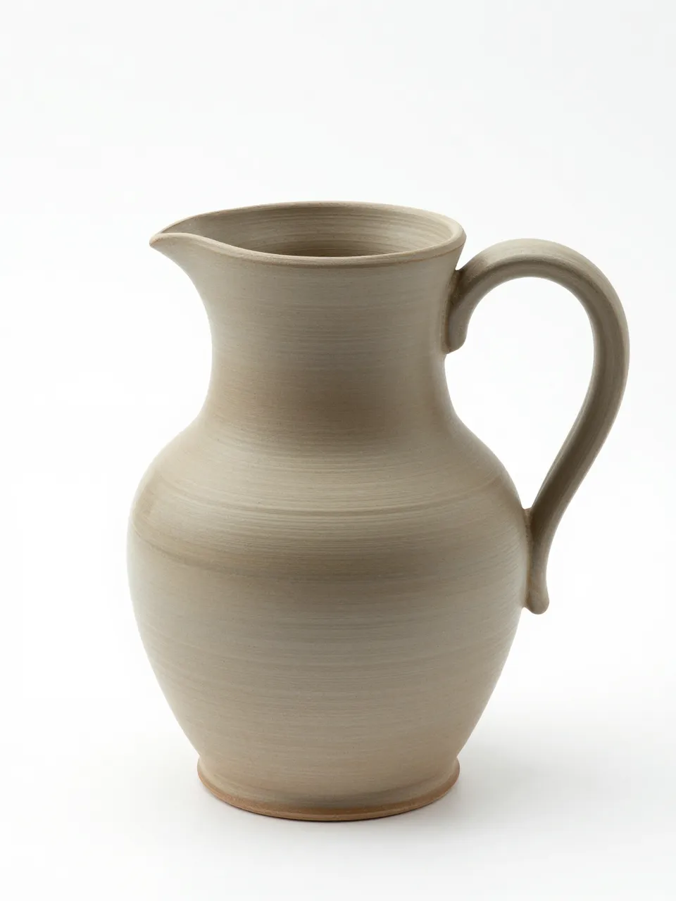 An unglazed hand-thrown clay pitcher with a pressed rim sits against a plain white studio background