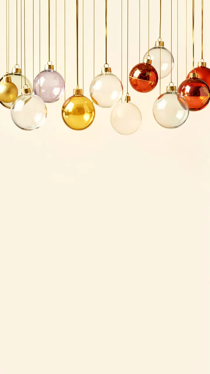 Glass and metallic Christmas baubles hang from thin gold threads against an empty cream background