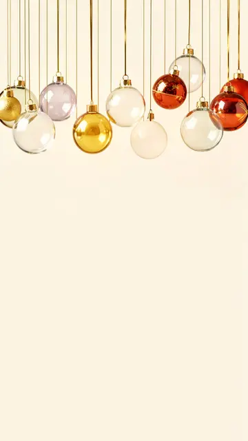 Glass and metallic Christmas baubles hang from thin gold threads against an empty cream background