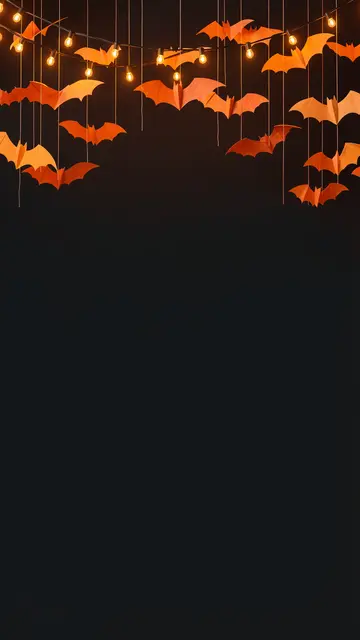 Orange paper bats and warm string lights hang from the top above empty dark copy space