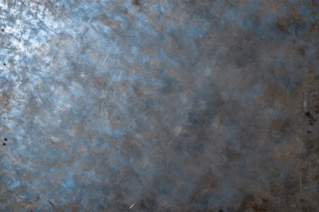 Scratched heat-tinted steel surface with soft blue and weathered bronze patina tones