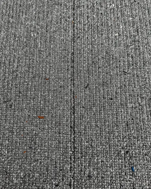 Full frame close-up of heather gray tweed fabric with coarse weave and scattered blue and rust flecks