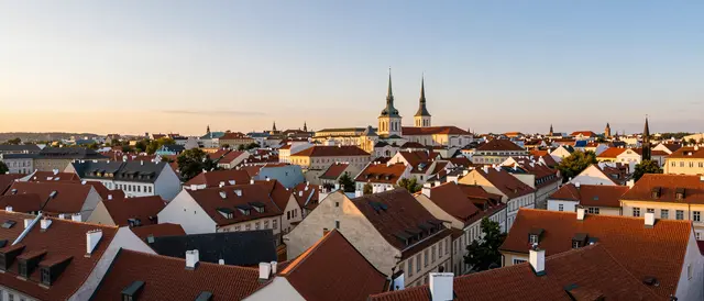Panoramic elevated view of dense historic european city rooftops lit by warm sunset light