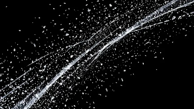 Diagonal streaks of icy sleet and small snow flakes drift across a solid pure black background