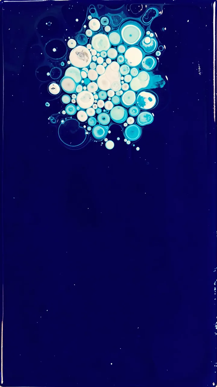 Vertical abstract acrylic pour with a bright white and aqua bubble cluster near the top of a deep indigo background