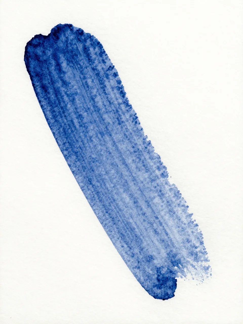 A dry brushed indigo watercolor streak rests on rough textured white watercolor paper under flat light