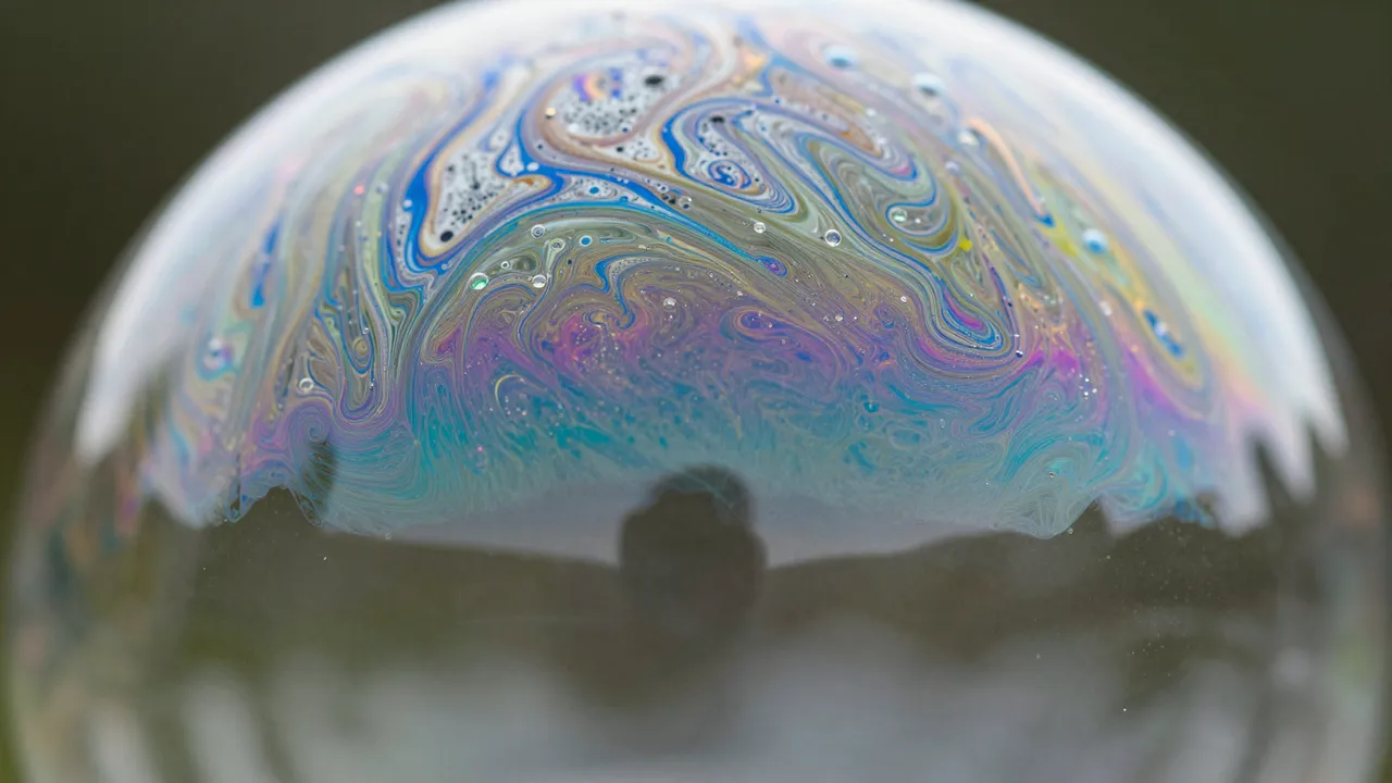 Close-up macro view of swirling iridescent color patterns across the curved surface of a soap bubble