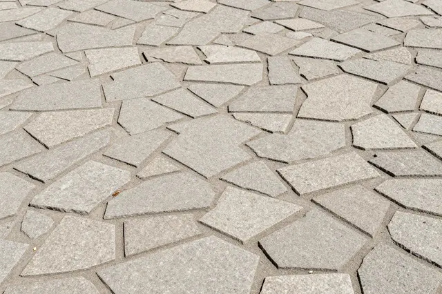 Full frame close-up of light gray irregular stamped flagstone concrete pavement in bright sunlight