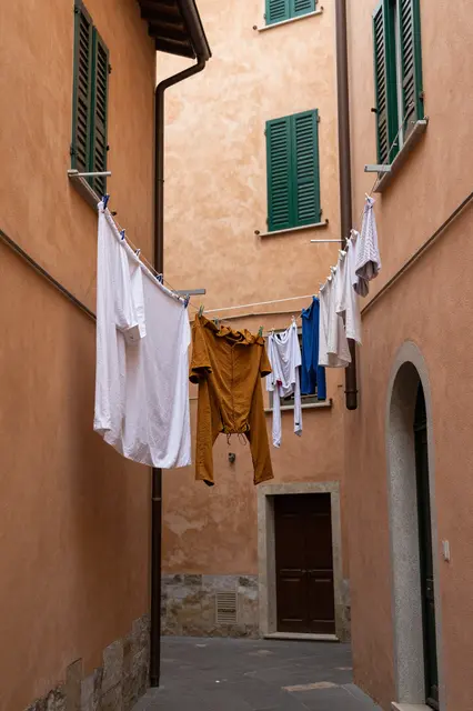 Laundry hangs on lines strung between ochre plaster walls of a narrow residential Italian alley