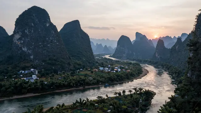 Aerial view of misty karst peaks lining a winding river at sunrise in southern China