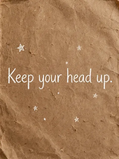 White hand-drawn text "Keep your head up." with small doodled stars on crumpled brown kraft paper