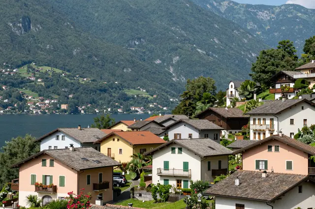Pastel villas sit on a hillside beside a blue lake backed by green northern Italian mountains