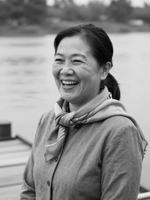 Black and white close-up portrait of a laughing mature Southeast Asian woman on a riverside dock