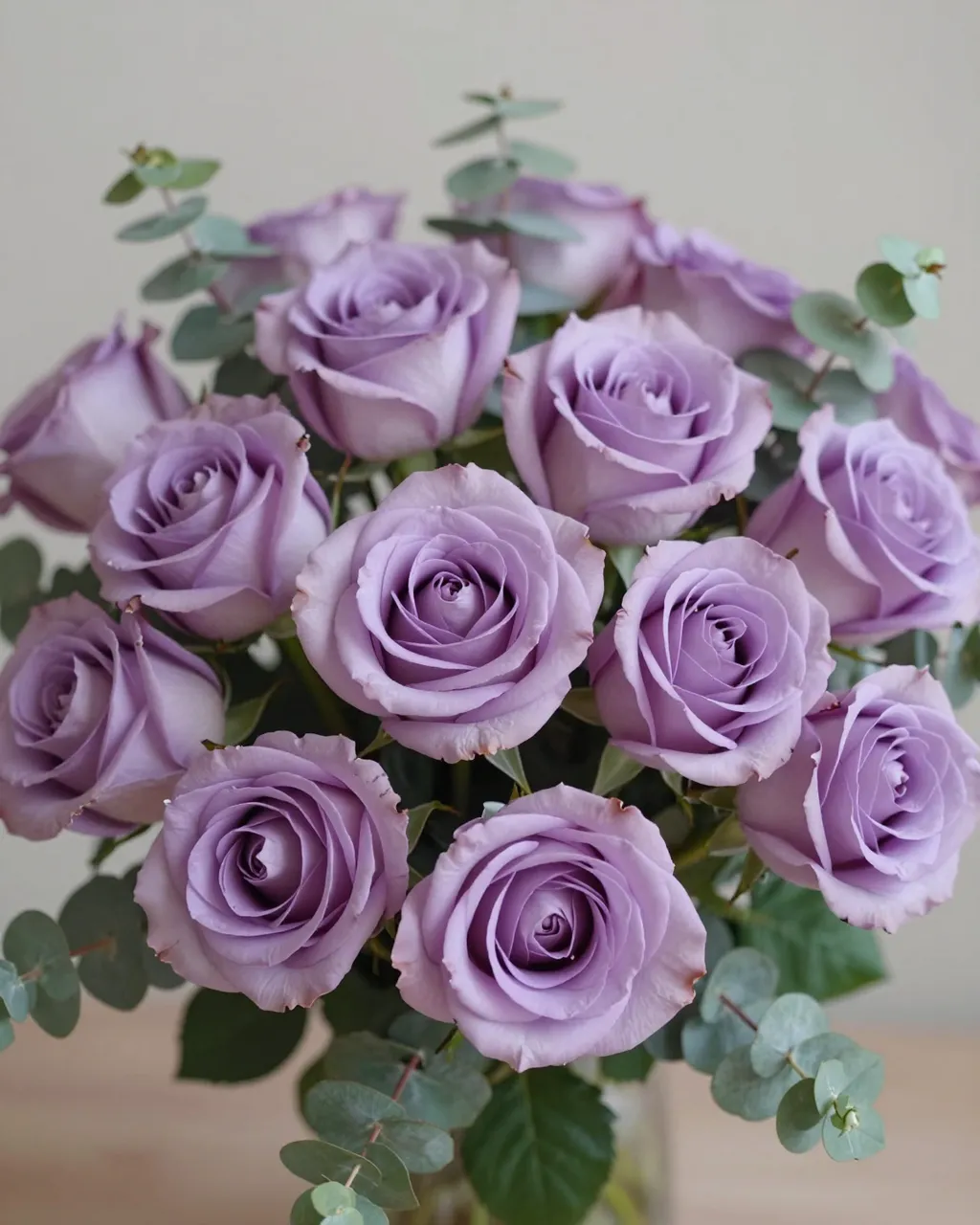 A neatly arranged bouquet of soft lavender roses paired with silvery eucalyptus foliage