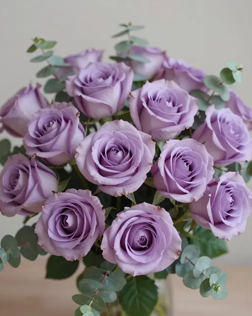 A neatly arranged bouquet of soft lavender roses paired with silvery eucalyptus foliage