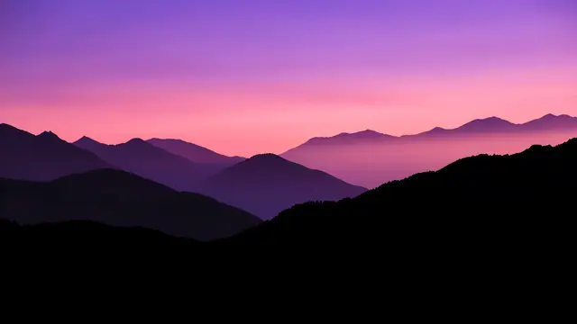 Black and purple layered mountain ridges stand against a smooth violet to rose twilight sky.