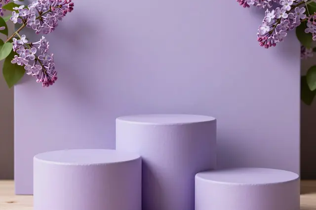Three lilac cylinder product podiums of varying heights sit against a lavender backdrop framed by lilac flower branches.