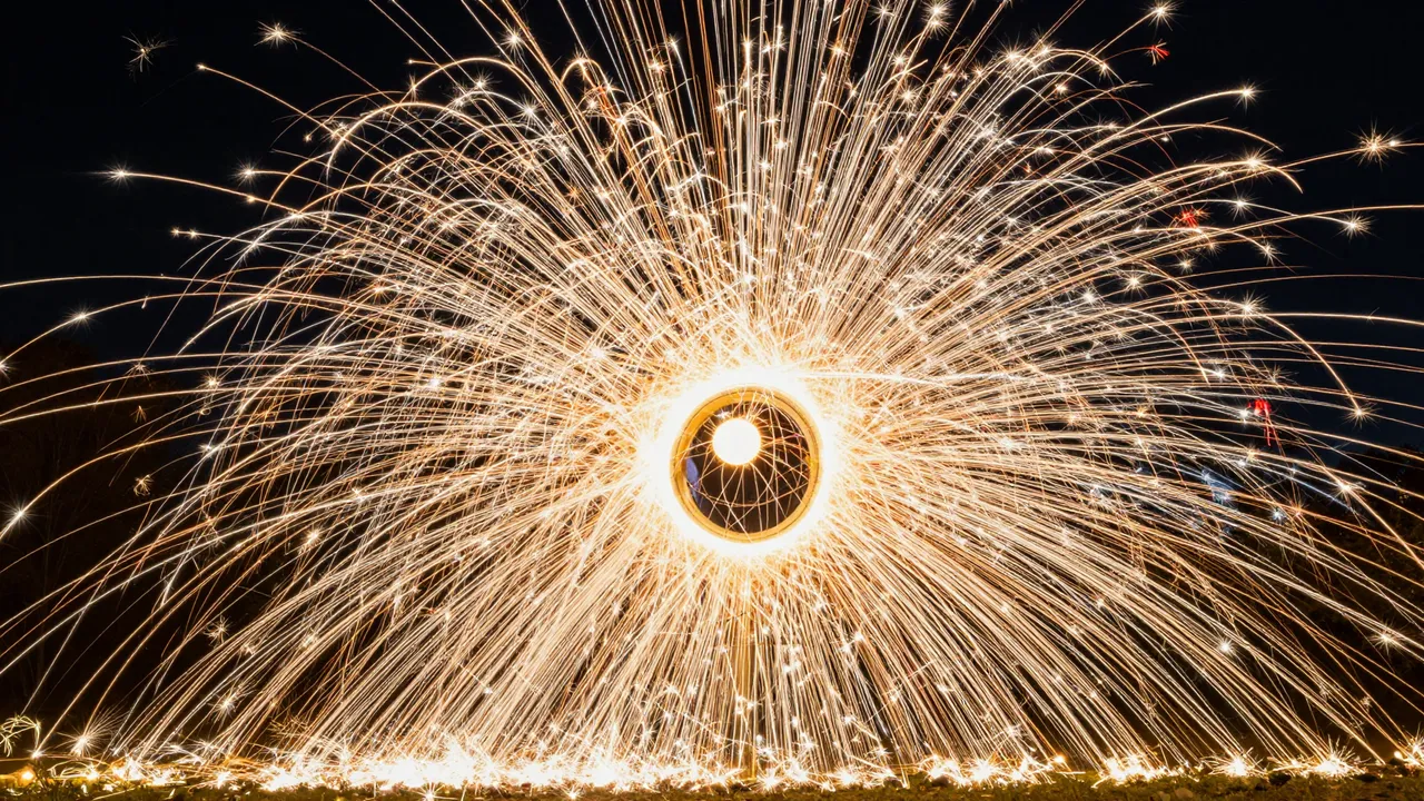 Bright golden sparks streak outward from a central glowing circle against a dark night sky