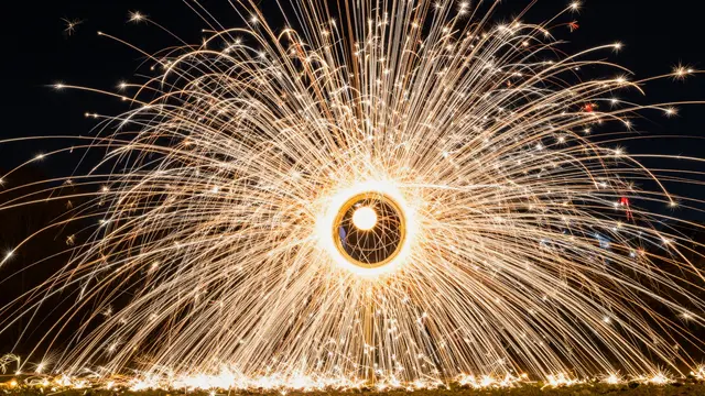 Bright golden sparks streak outward from a central glowing circle against a dark night sky