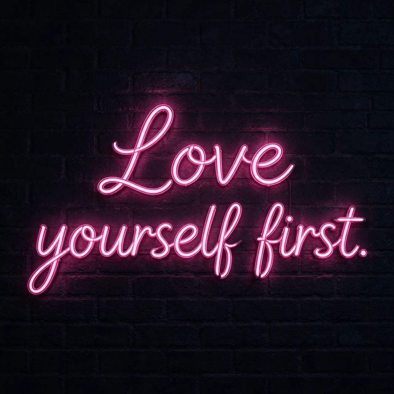 Pink neon script sign reading "Love yourself first." glows on a dark brick wall at night