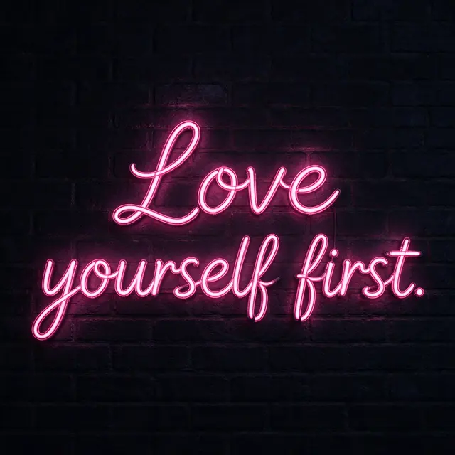 Pink neon script sign reading "Love yourself first." glows on a dark brick wall at night
