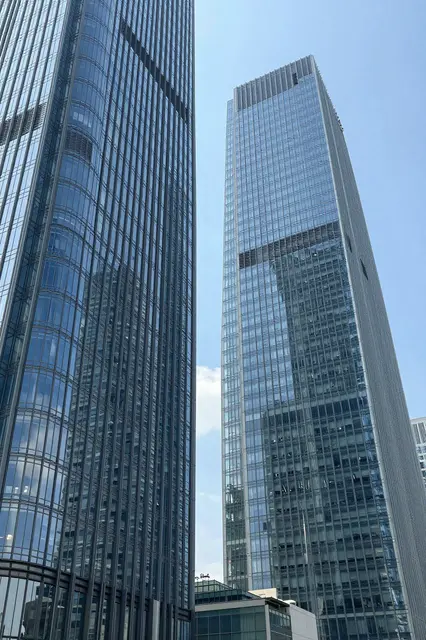 Upward view of modern glass skyscrapers reflecting blue sky between the building facades
