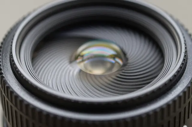 Close up macro shot of the front glass element of a camera lens with iridescent light refraction
