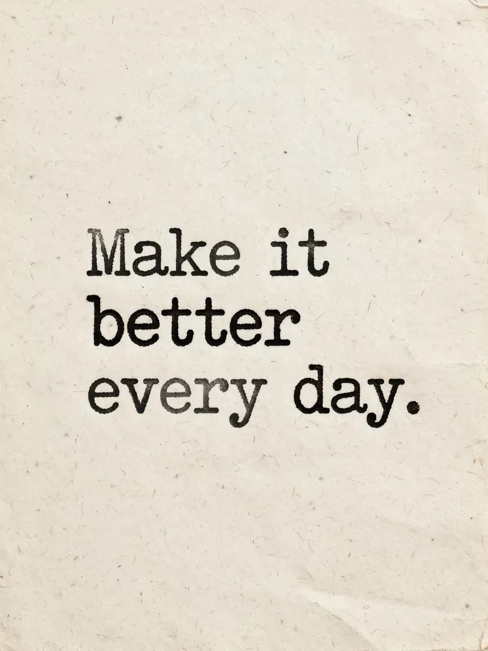 Typewriter-style text reading "Make it better every day." printed on warm textured off-white paper