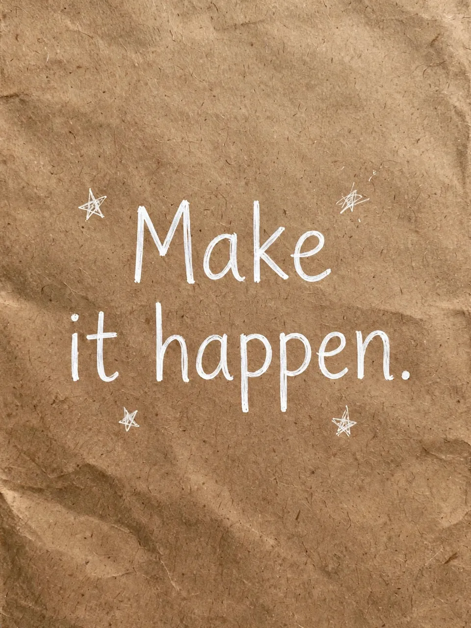 White hand-drawn "Make it happen." lettering with small doodle stars on crumpled brown kraft paper