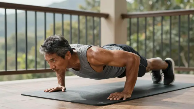 Middle aged man holds a plank position on an exercise mat on a sunlit balcony with a mountain view