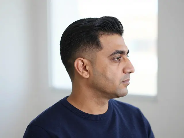 Profile view of a forties Middle Eastern man with a mid fade haircut wearing a navy sweater by soft window light