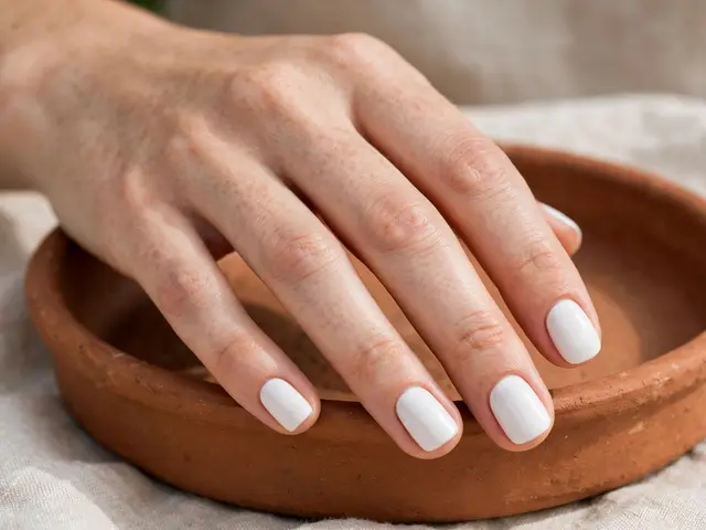 Fair-skinned hand with short opaque white squoval nails resting on a small terracotta dish
