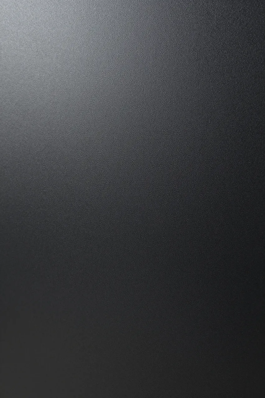 Full frame close-up of fine bumpy powder-coated matte black steel with soft gradient lighting