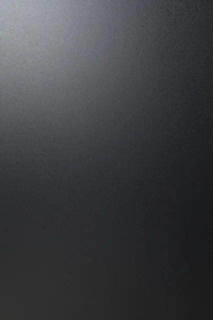 Full frame close-up of fine bumpy powder-coated matte black steel with soft gradient lighting