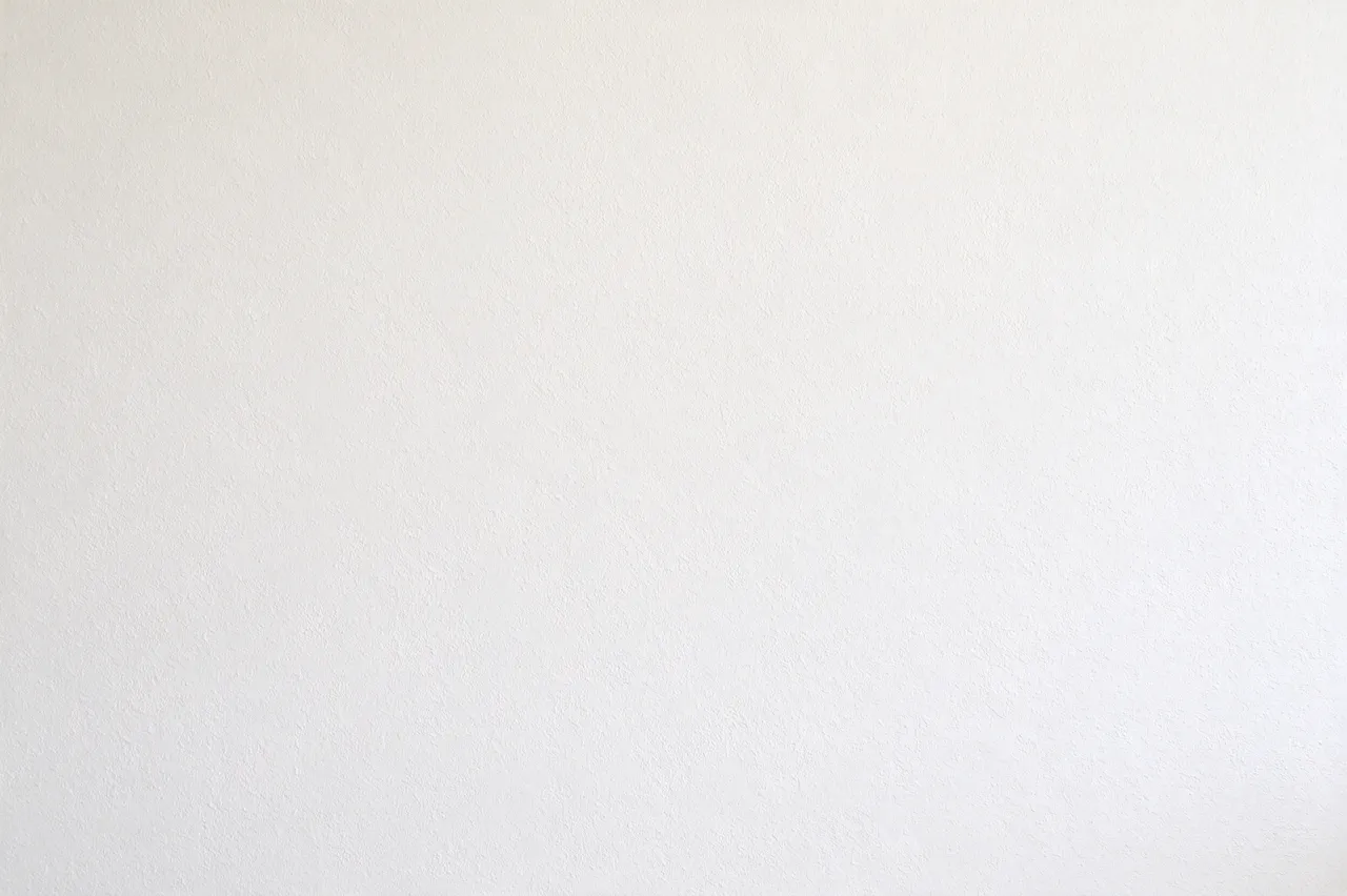 Full frame view of smooth matte warm white level five drywall with faint stipple texture under flat even lighting