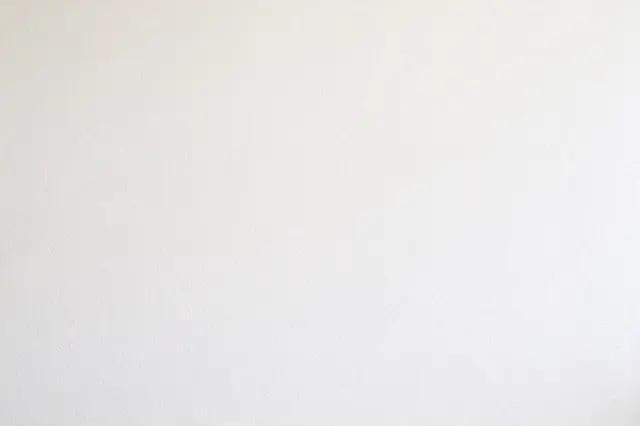 Full frame view of smooth matte warm white level five drywall with faint stipple texture under flat even lighting